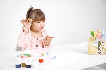 retrato-de-uma-menina-encantadora-com-sindrome-de-down-brincando-com-ovos-coloridos-de-pascoa